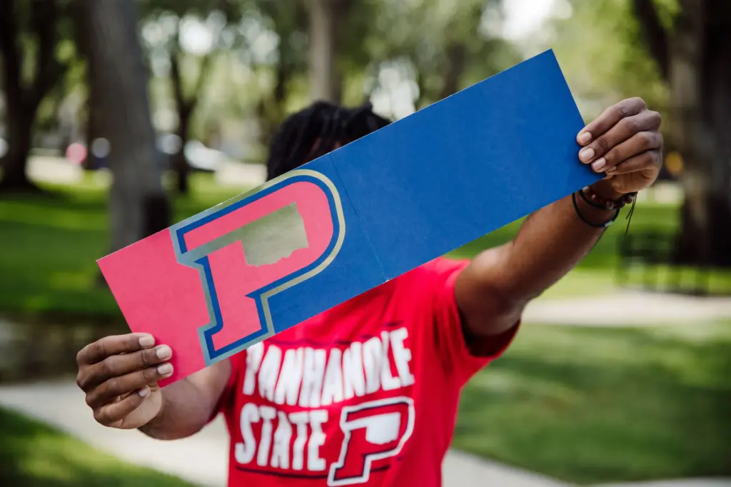OPSU Student holding an OPSU acceptance letter over their face