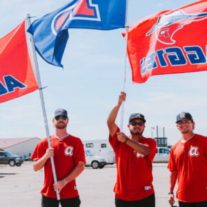 3 members of the OPSU baseball team holding up Aggie Flags.